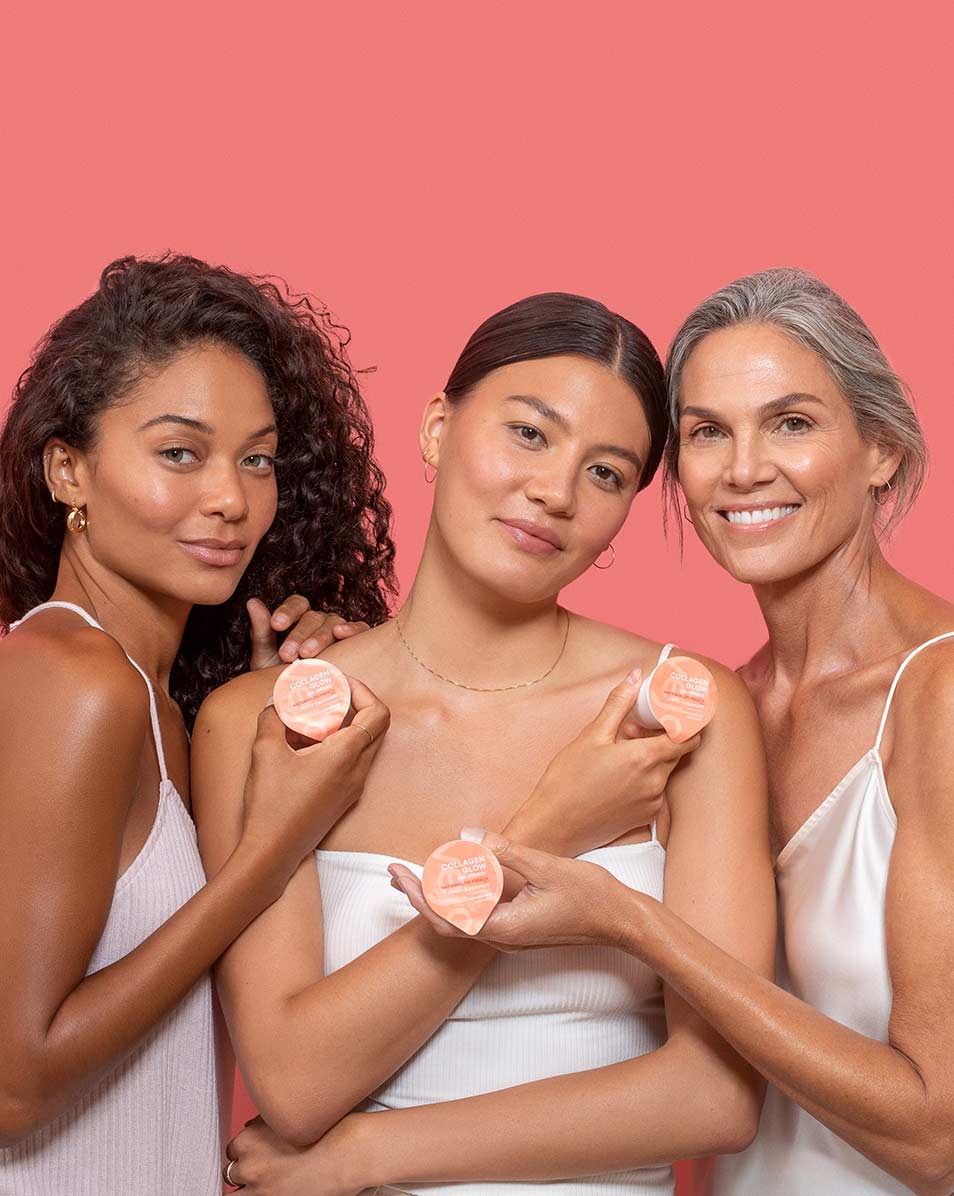 Three women of all ages standing in front of a pink backdrop holding Vejo's Collagen Glow blend.